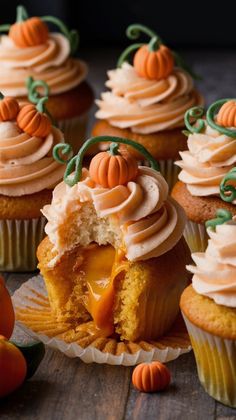 several cupcakes with frosting and pumpkin decorations on them sitting on a table