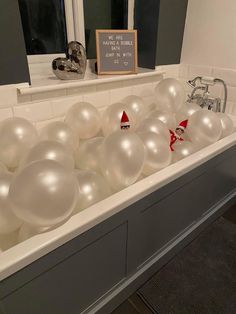 a bathtub filled with white balloons and elf hats