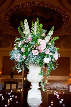 a vase filled with pink and white flowers on top of a wooden table covered in confetti