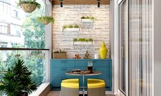 a small balcony with blue cabinets and yellow stools next to potted plants on the windowsill