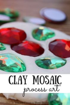 clay mosaic process art with red, green and white stones in the center on a wooden surface