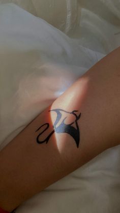 a person laying in bed with a tattoo on their arm