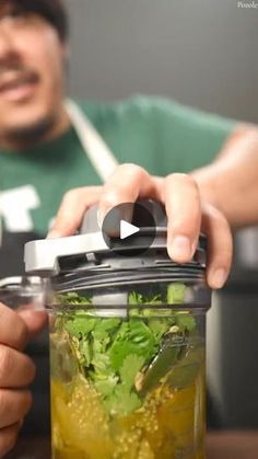 a man is holding a blender full of green liquid and vegetables to make a smoothie