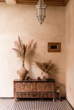 two vases on top of a table in a room with black and white tile flooring