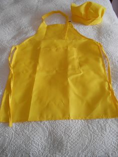 a yellow apron sitting on top of a white bed