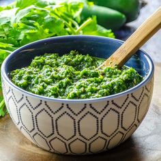 a bowl filled with green pesto next to lettuce