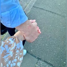 two people holding hands while walking down the street