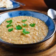 a bowl of oatmeal with green garnish in it on a wooden table