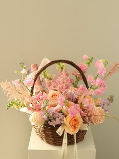 a basket filled with lots of flowers on top of a white table next to a wall