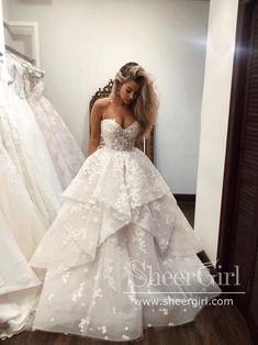 a woman standing in front of a mirror wearing a wedding dress with flowers on it