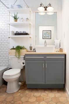 a white toilet sitting next to a sink in a bathroom under a mirror and lights