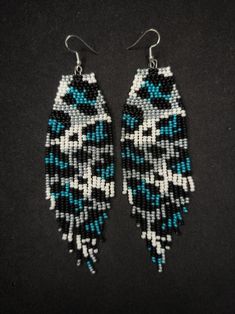 two pairs of beaded earrings with blue and white designs on black background, side by side