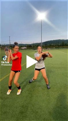 two girls are playing softball on a field with the sun in the sky behind them