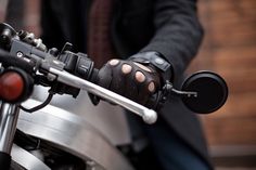 a close up of a person's hand on a motorcycle handlebar and glove