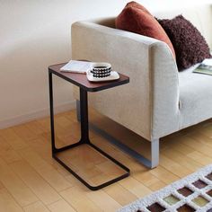 a small table with a book on it next to a white couch and brown pillows