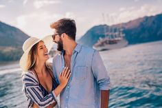 a man and woman standing next to each other near the water