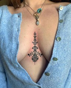 a woman's chest with an intricate tattoo design on her chest and the upper part of her breast