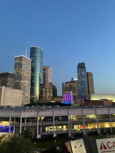 the city skyline is lit up at night, with skyscrapers in the foreground