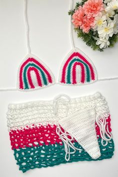 two crocheted bikinisuits are shown next to flowers and a pot holder