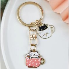 a keychain with a cat in a cup on it sitting on a plate