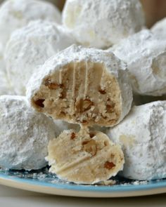 several pieces of dessert on a plate with powdered sugar and nuts in the middle