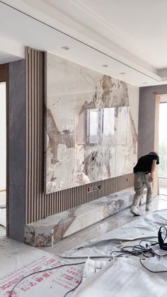 a man standing on top of a hard wood floor next to a wall covered in paint