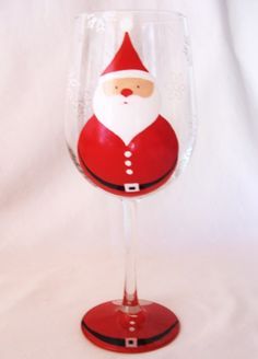 a red wine glass with a santa clause painted on it's face and bottom