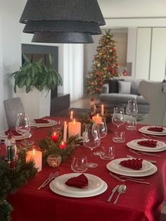 a dining room table set for christmas with candles and place settings on the dinner table