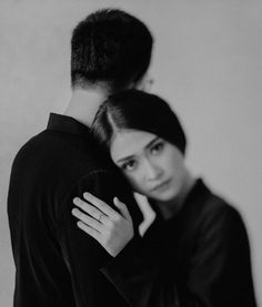 black and white photograph of a man hugging a woman's neck with her hand on her shoulder