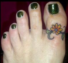 a woman's foot with a flower tattoo on the toe and green nail polish