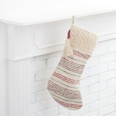 a christmas stocking hanging from a fireplace with white brick wall in the back ground