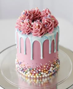 a pink and blue cake with sprinkles on it sitting on a glass plate