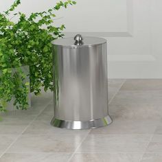 a stainless steel trash can next to a potted plant