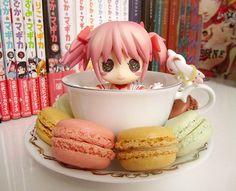 a doll is sitting in a cup with doughnuts on the plate next to it