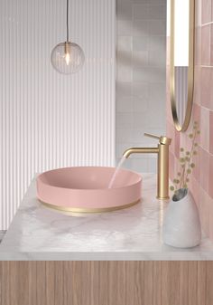 a bathroom sink with a pink bowl and gold faucet