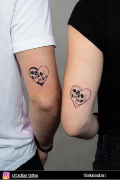 two people with tattoos on their arms holding hands and looking at each other's faces