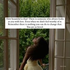 a woman standing in front of an open window looking up at the sky and trees