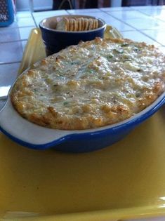 a casserole dish on a yellow tray with a bowl of crackers in the background