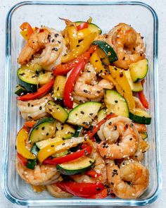 a glass dish filled with shrimp, zucchini, and bell pepper stir fry