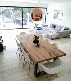 a dining room table with chairs and a vase on top of it in front of a couch