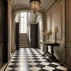 a hallway with black and white checkered flooring, chandelier and two lamps