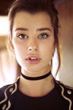 a close up of a person wearing a choker and looking at the camera with a serious look on her face