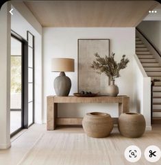 a living room with two vases on the table and stairs in the back ground