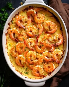 a casserole dish filled with shrimp and grits, garnished with parsley