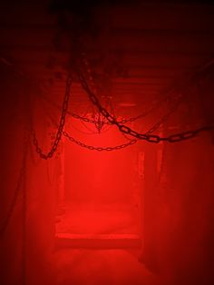 a red light in the middle of a room with chains hanging from it's ceiling