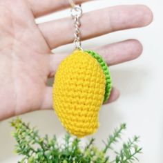 a hand is holding a tiny keychain made to look like a lemon