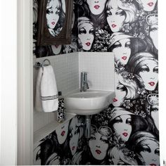 a bathroom with a sink, mirror and wallpaper in black and white color scheme