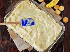 a wooden table topped with a cake covered in white frosting and two banana's