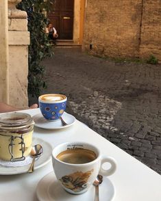 two cups of coffee sit on a table outside