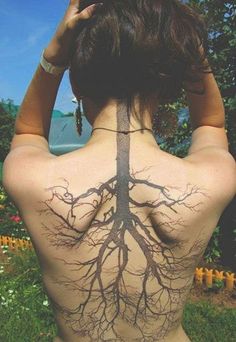 the back of a woman's body with tree roots on her upper and lower back